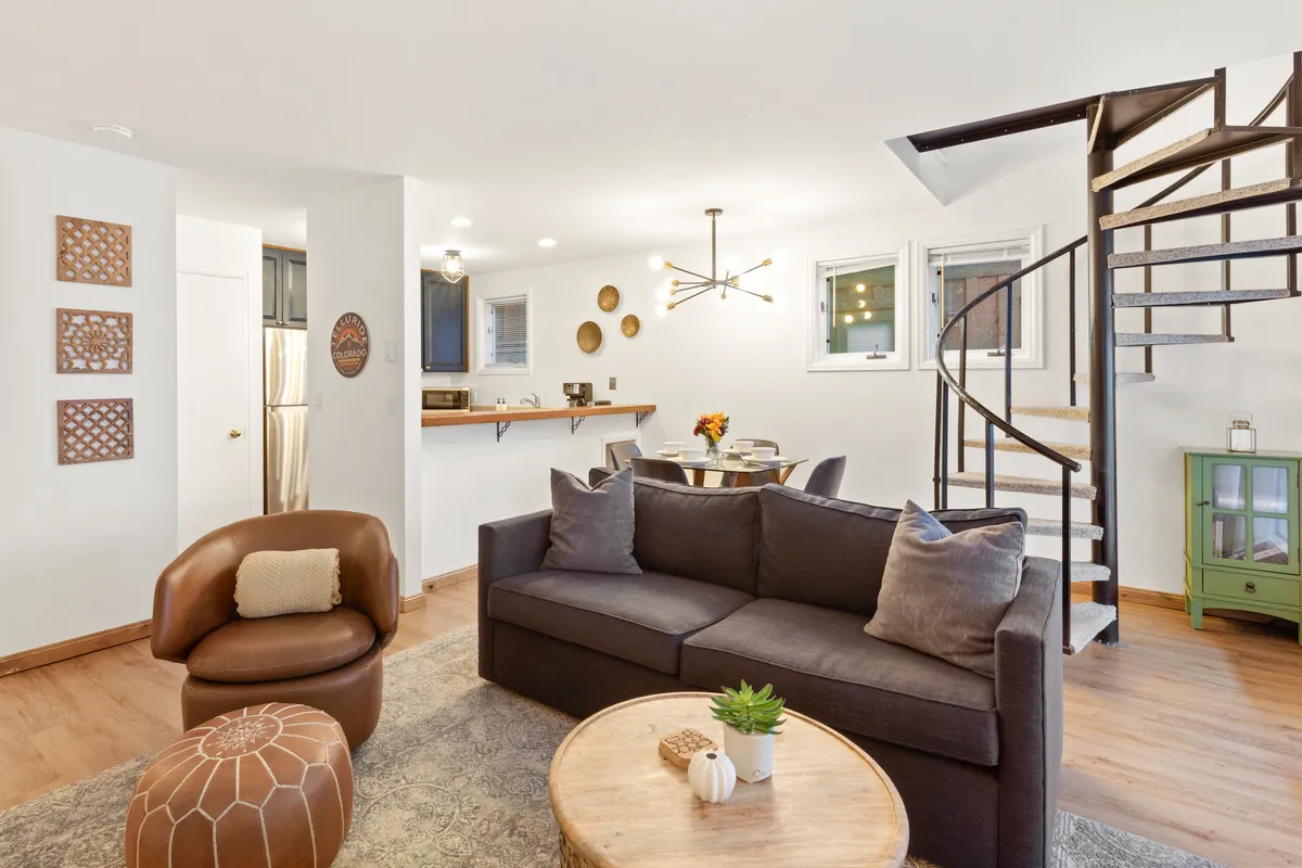 A cozy, inviting space with a plush sofa, view of the spiral staircase, adjacent dining table, and colorful wall art. The arrangement encourages conversation and togetherness, with a blend of comfort and style.