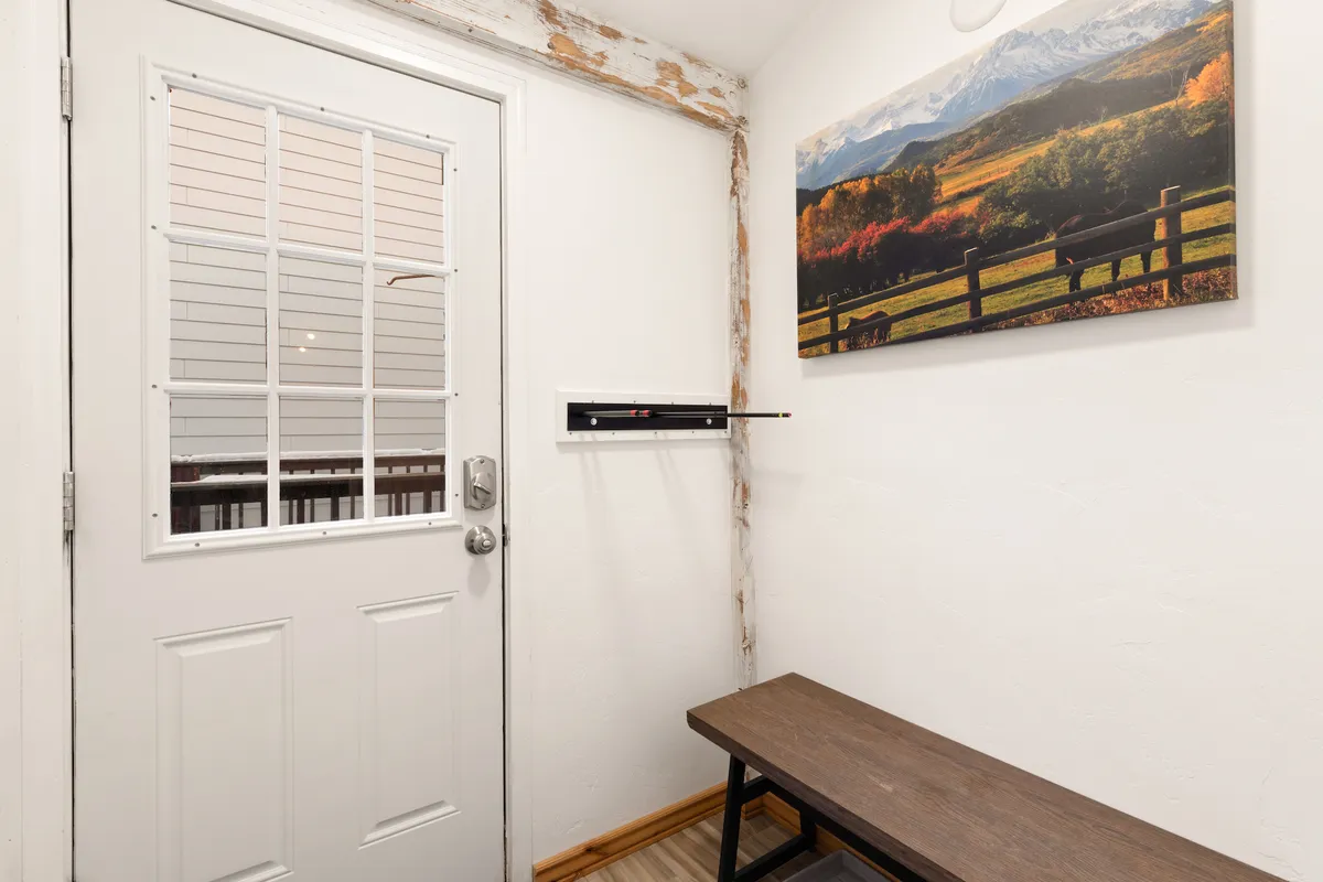The entrance area showcases a sturdy door, a practical bench for sitting or storing items, and a large landscape artwork. The space is inviting and organized, ideal for managing outdoor gear and welcoming guests.